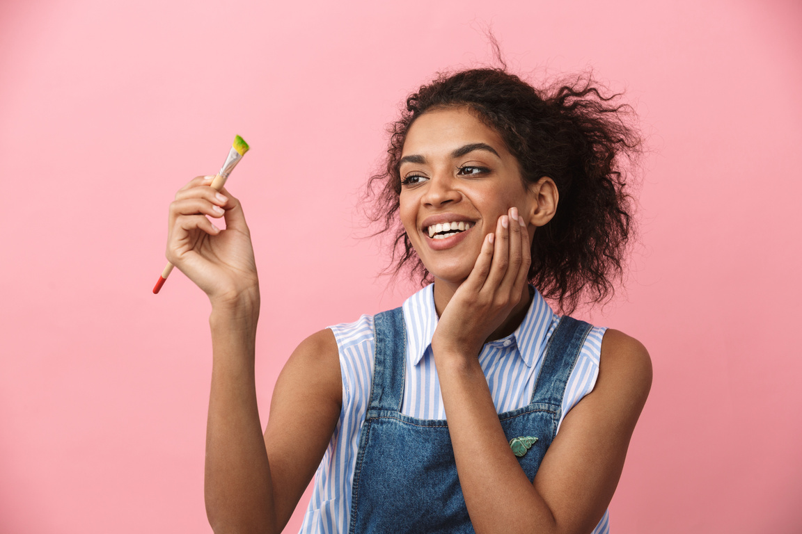 Woman Painter Posing Isolated over Pink Wall Background Holding Painting Brush